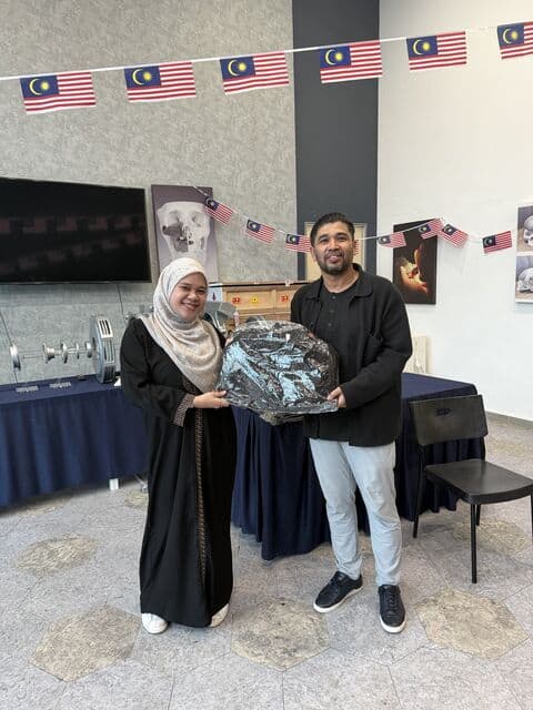 Team member in a grey hijab receives a 3D Gens bomber jacket