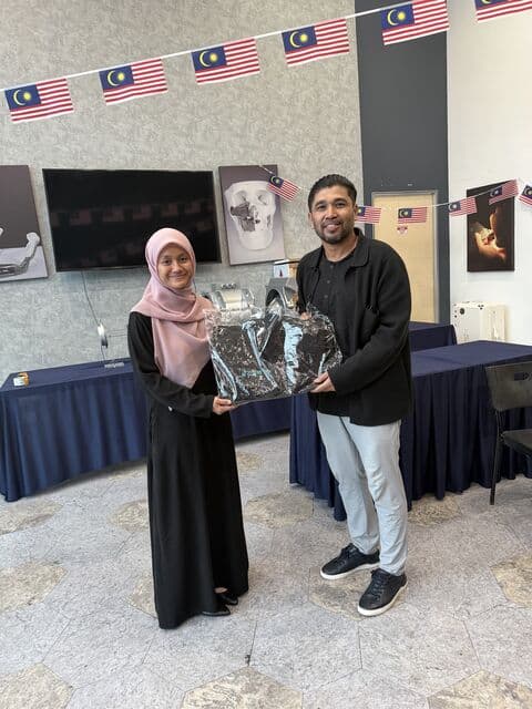 Team member in a pink hijab receives a 3D Gens bomber jacket
