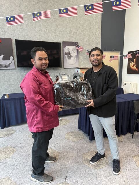Team member in a red jacket receives a 3D Gens bomber jacket