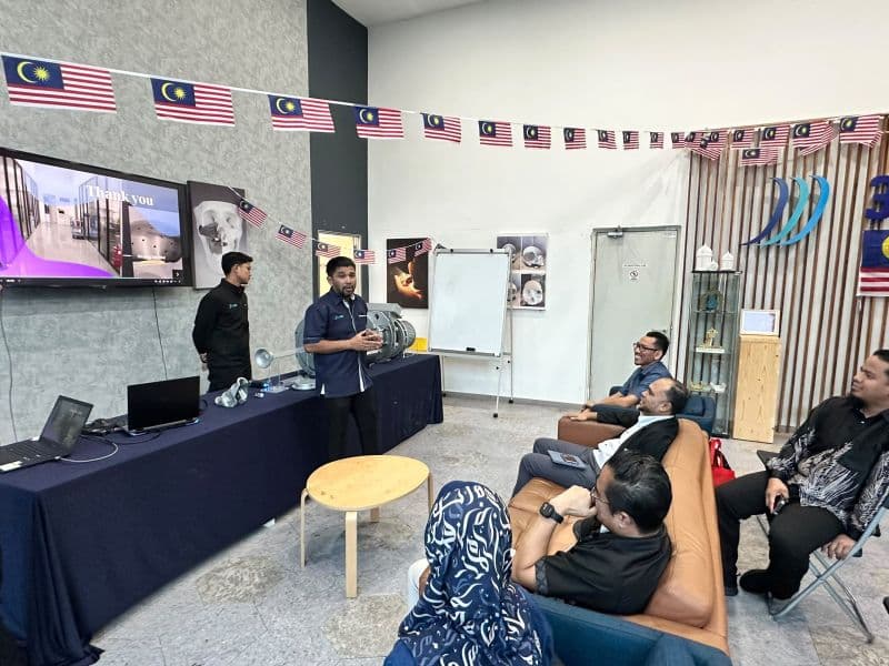 A speaker presents to seated guests at the 3D Gens office